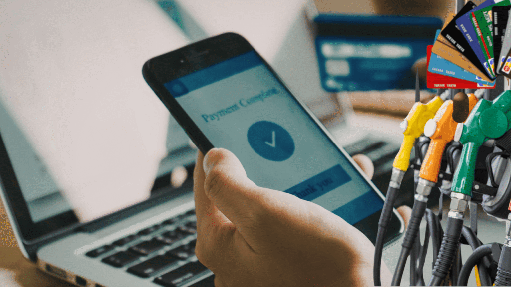 Hand holding a smartphone with a completed payment screen near fuel pumps and payment cards, representing Fuel Budgets With Fuel Cards for better fuel spending control and fleet cost management.