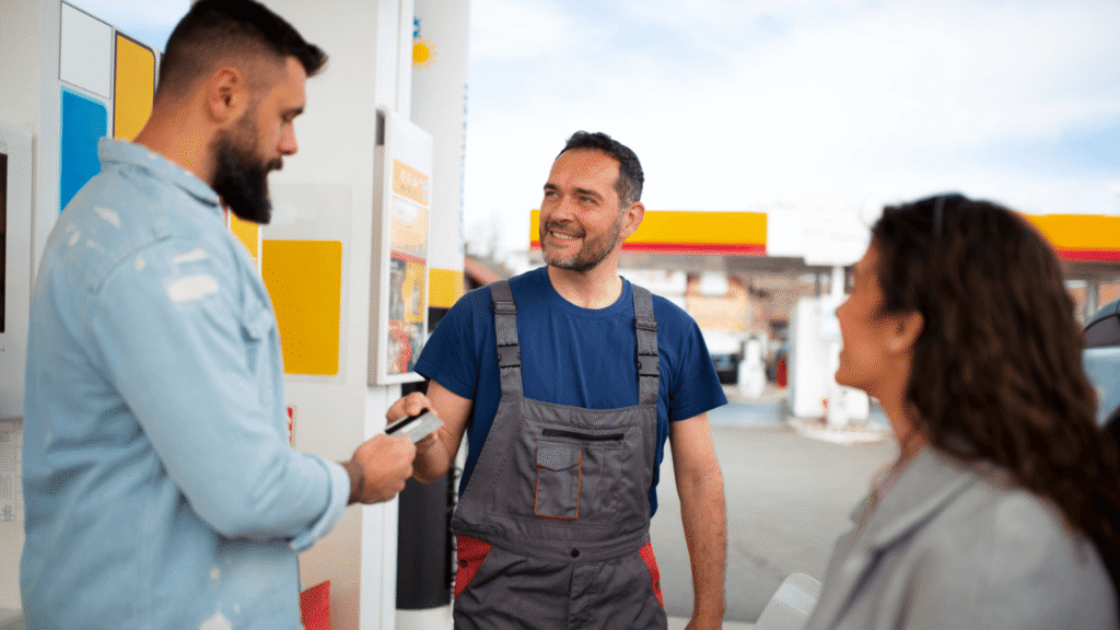 Fuel card controls image showing a fleet manager and driver reviewing fueling and payment details at a gas station, illustrating monitoring, authorization, and controlled fuel card use.