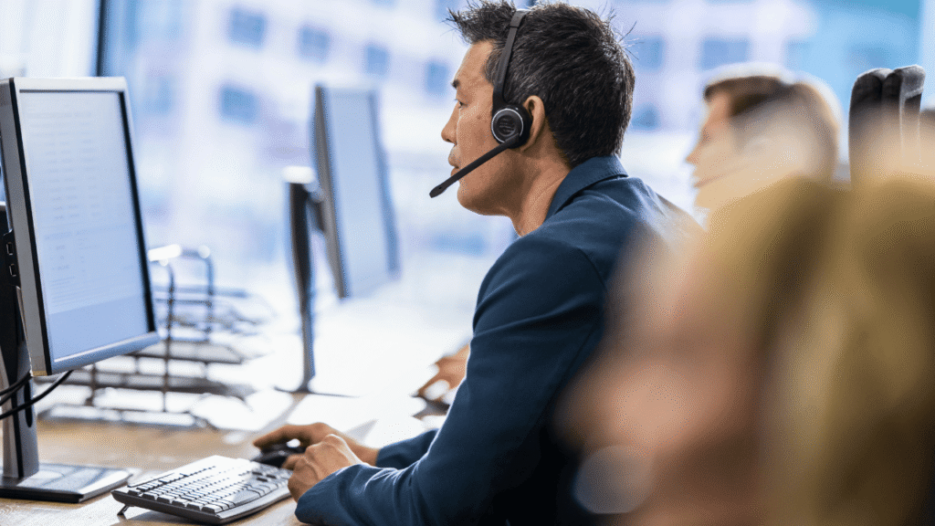 Fuel card customer support representative wearing a headset while assisting customers at a computer workstation in a modern office call center environment.