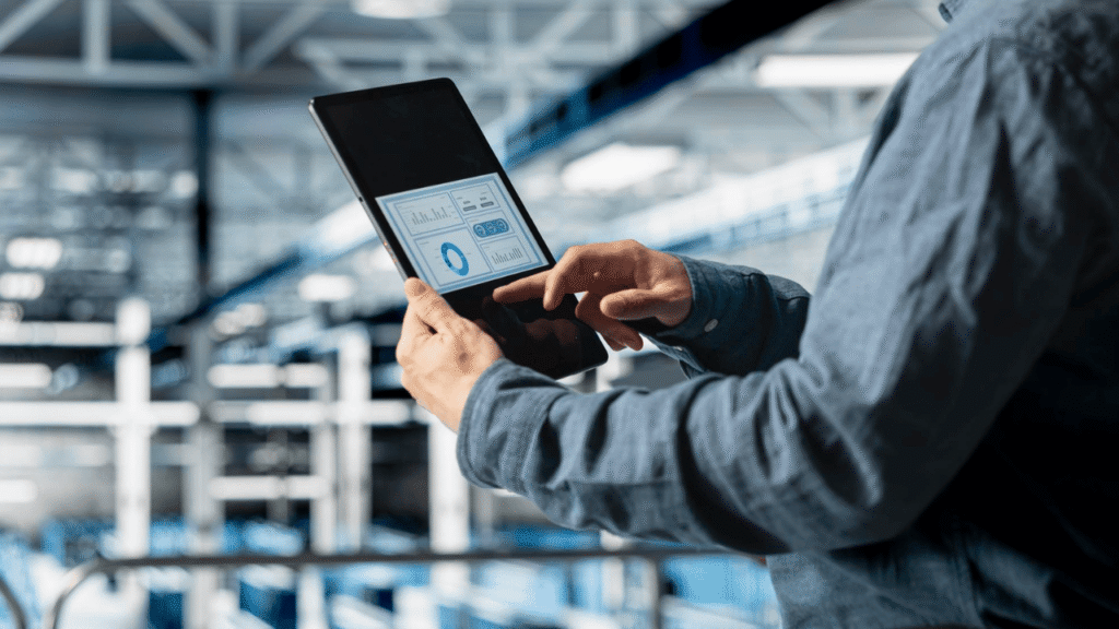 Person using a tablet dashboard in an industrial setting to monitor fleet software and real-time performance data.